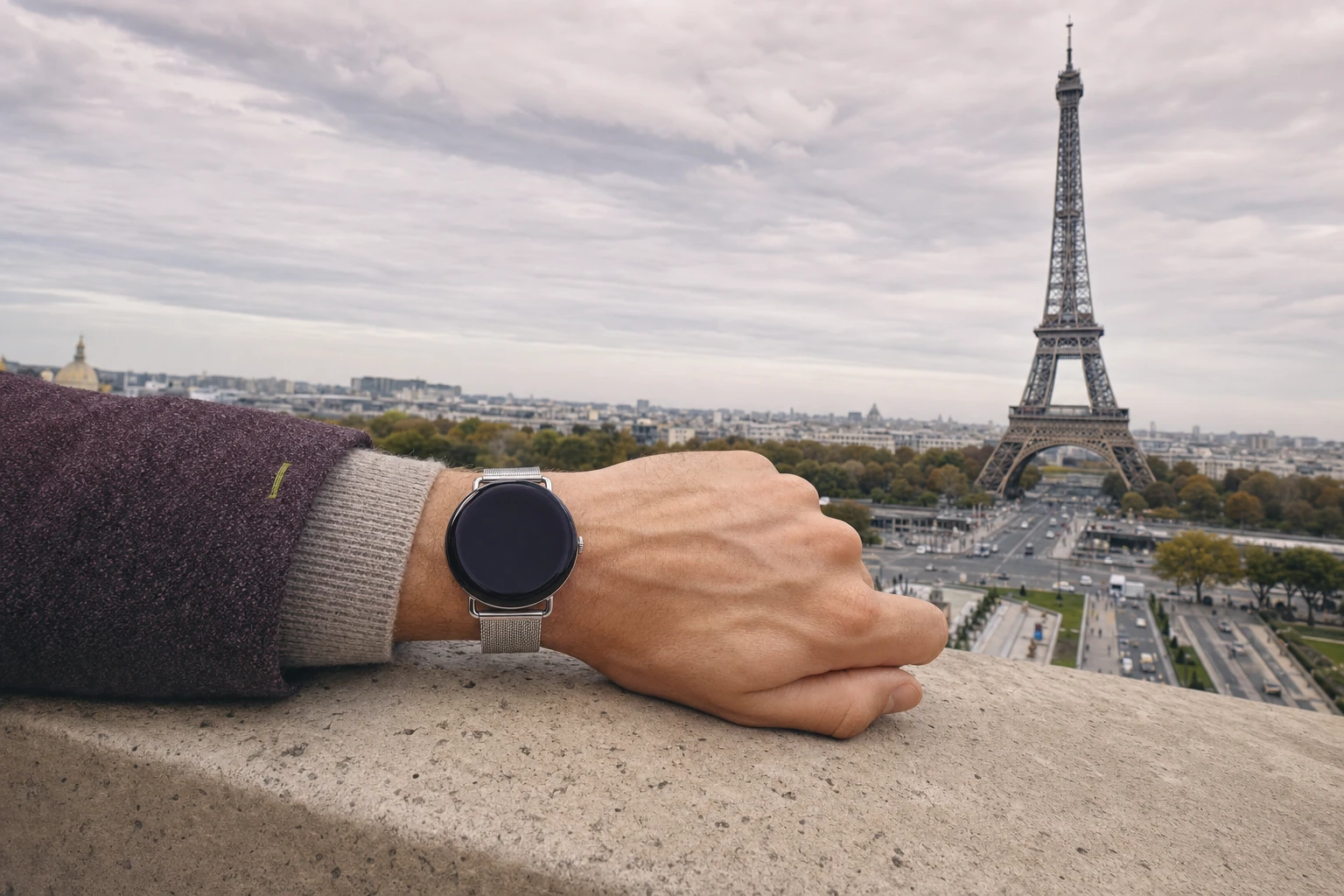 Ein Reisender legt das Handgelenk auf die Brüstung am Trocadéro — Eiffelturm und die runde Uhr von Roam O'Clock sind beide im Bild